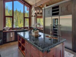 Experience luxury mountain living in this stunning kitchen, featuring a large granite island with a sink and ample seating.