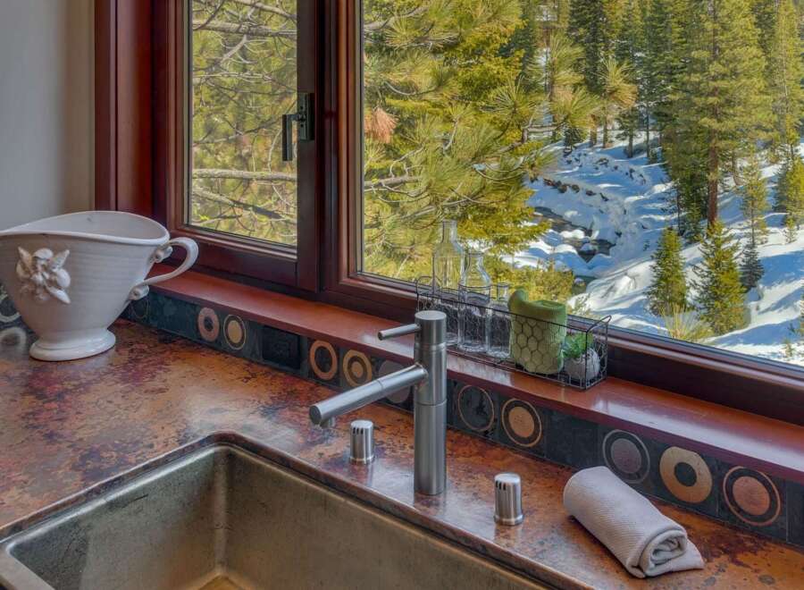 Experience breathtaking mountain views from this stunning kitchen, featuring a unique copper countertop and a deep stainless steel sink.