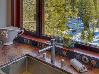 Experience breathtaking mountain views from this stunning kitchen, featuring a unique copper countertop and a deep stainless steel sink.