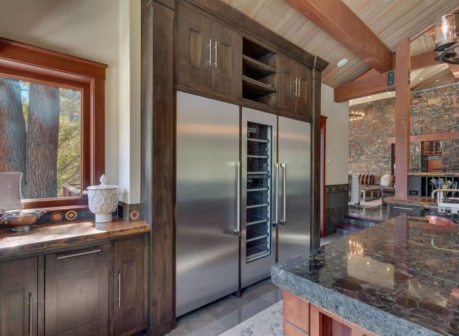 Experience luxury living in this stunning kitchen featuring a built-in stainless steel refrigerator and wine cooler, complemented by rich dark wood cabinetry.