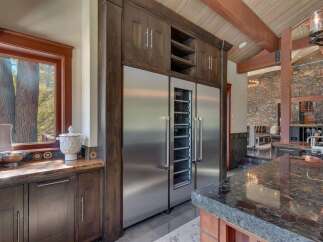 Experience luxury living in this stunning kitchen featuring a built-in stainless steel refrigerator and wine cooler, complemented by rich dark wood cabinetry.