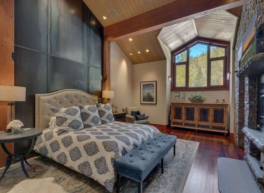 Experience luxury mountain living in this stunning bedroom featuring a king-sized bed with a tufted headboard and elegant patterned bedding.