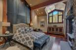 Experience luxury mountain living in this stunning bedroom featuring a king-sized bed with a tufted headboard and elegant patterned bedding.