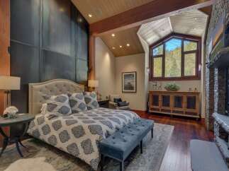 Experience luxury mountain living in this stunning bedroom featuring a king-sized bed with a tufted headboard and elegant patterned bedding.