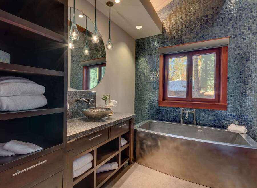Experience luxury in this stunning bathroom featuring a sleek, modern soaking tub and a unique vessel sink atop a granite vanity.