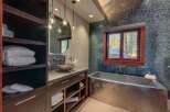 Experience luxury in this stunning bathroom featuring a sleek, modern soaking tub and a unique vessel sink atop a granite vanity.