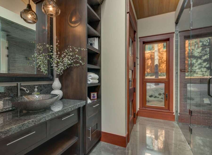 Experience luxury in this stunning bathroom featuring a vessel sink atop a granite countertop and dark wood cabinetry.