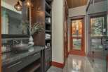 Experience luxury in this stunning bathroom featuring a vessel sink atop a granite countertop and dark wood cabinetry.