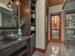 Experience luxury in this stunning bathroom featuring a vessel sink atop a granite countertop and dark wood cabinetry.