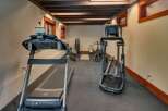 This home gym features a treadmill and elliptical for cardio workouts, alongside a weight bench and rack for strength training.