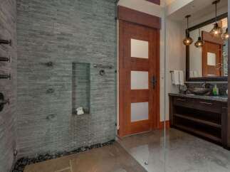 Experience luxury in this modern bathroom featuring a spacious walk-in shower with multiple showerheads and sleek stone tilework.
