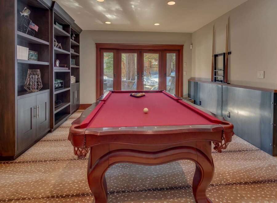 Experience ultimate entertainment in this game room, featuring a classic red felt pool table perfect for friendly matches.