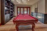 Experience ultimate entertainment in this game room, featuring a classic red felt pool table perfect for friendly matches.