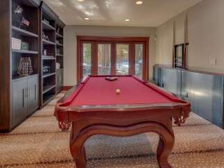Experience ultimate entertainment in this game room, featuring a classic red felt pool table perfect for friendly matches.