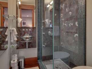 Experience luxury in this modern bathroom featuring a sleek glass-enclosed shower with unique fossil-patterned marble walls.