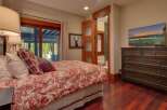Experience rustic charm in this inviting bedroom featuring a comfortable bed with a red and white toile duvet and plaid accent pillows.