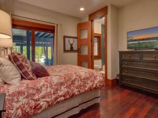 Experience rustic charm in this inviting bedroom featuring a comfortable bed with a red and white toile duvet and plaid accent pillows.