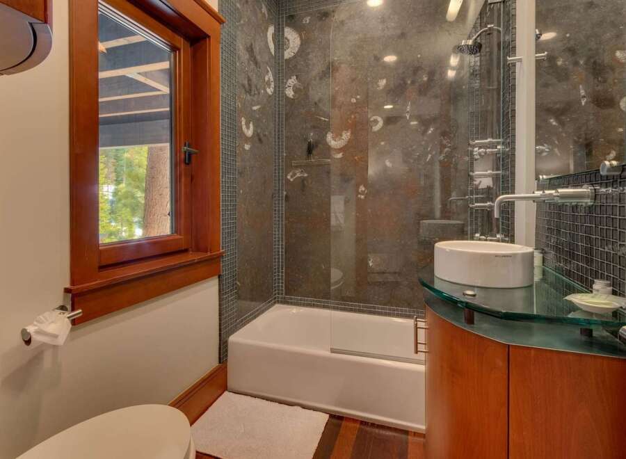 Experience luxury in this modern bathroom featuring a sleek glass-enclosed shower with unique fossil-inspired tilework.