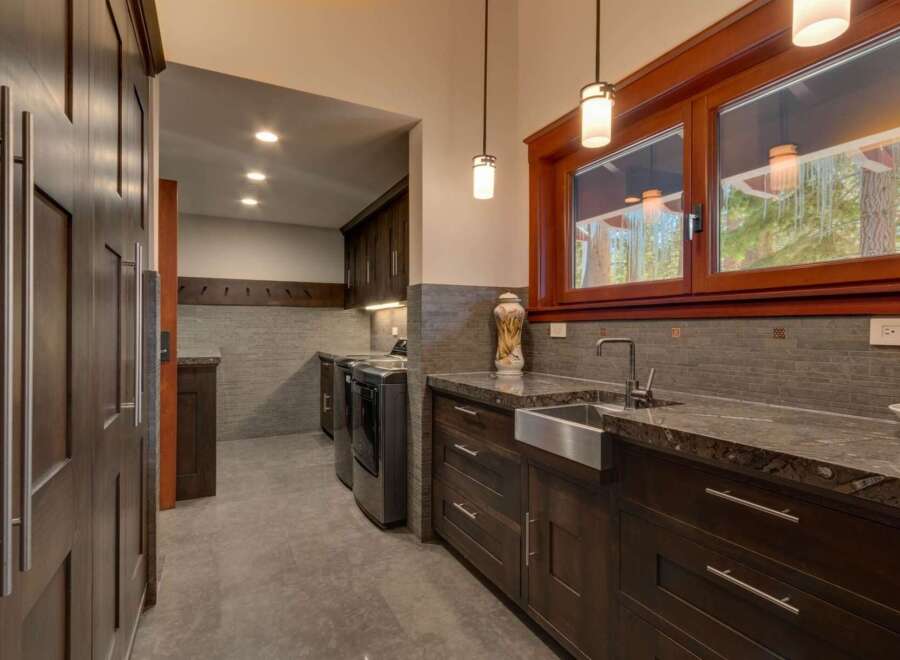 Discover this spacious laundry room featuring dark wood cabinetry and granite countertops.