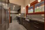 Discover this spacious laundry room featuring dark wood cabinetry and granite countertops.