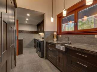 Discover this spacious laundry room featuring dark wood cabinetry and granite countertops.