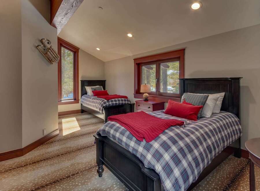 This charming bedroom features two twin beds with cozy plaid bedding and vibrant red accents, perfect for a guest room or children's space.