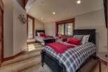 This charming bedroom features two twin beds with cozy plaid bedding and vibrant red accents, perfect for a guest room or children's space.