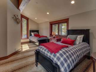 This charming bedroom features two twin beds with cozy plaid bedding and vibrant red accents, perfect for a guest room or children's space.