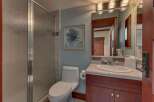 This bathroom features a sleek glass-enclosed shower and a modern toilet, complemented by a vanity with a granite countertop and a large, ornate mirror.