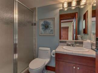 This bathroom features a sleek glass-enclosed shower and a modern toilet, complemented by a vanity with a granite countertop and a large, ornate mirror.