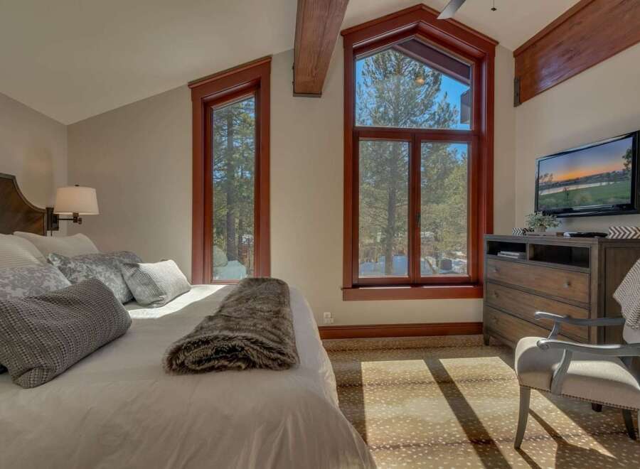 Experience cozy mountain living in this charming bedroom, featuring a plush bed adorned with decorative pillows and a luxurious faux fur throw.