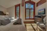 Experience cozy mountain living in this charming bedroom, featuring a plush bed adorned with decorative pillows and a luxurious faux fur throw.