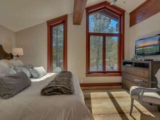 Experience cozy mountain living in this charming bedroom, featuring a plush bed adorned with decorative pillows and a luxurious faux fur throw.