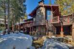Experience luxury mountain living in this stunning stone and wood home, nestled amongst tall pine trees and surrounded by snow-covered grounds.