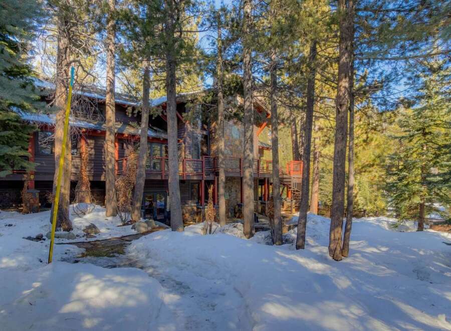 Nestled amidst tall pine trees, this stunning mountain home offers a serene winter retreat.