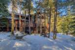 Nestled amidst tall pine trees, this stunning mountain home offers a serene winter retreat.