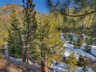 Experience the serene beauty of this mountain retreat, nestled amidst snow-dusted pines and a gentle stream.