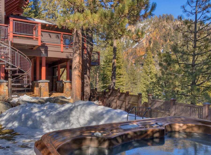 Experience luxury mountain living with this stunning property featuring a private hot tub overlooking a picturesque forest and snow-capped mountains.