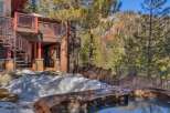 Experience luxury mountain living with this stunning property featuring a private hot tub overlooking a picturesque forest and snow-capped mountains.