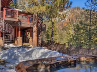 Experience luxury mountain living with this stunning property featuring a private hot tub overlooking a picturesque forest and snow-capped mountains.