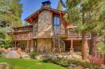 Experience luxury mountain living in this stunning timber-frame home, featuring a striking stone facade and expansive decks perfect for enjoying the surrounding pine forest.