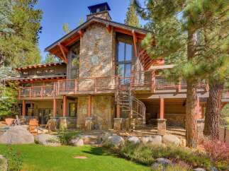 Experience luxury mountain living in this stunning timber-frame home, featuring a striking stone facade and expansive decks perfect for enjoying the surrounding pine forest.