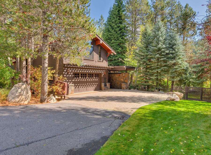 Nestled amidst towering pines and vibrant autumn foliage, this property boasts a charming rustic exterior with a spacious two-car garage.