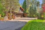 Nestled amidst towering pines and vibrant autumn foliage, this property boasts a charming rustic exterior with a spacious two-car garage.