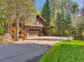 Nestled amidst towering pines and vibrant autumn foliage, this property boasts a charming rustic exterior with a spacious two-car garage.