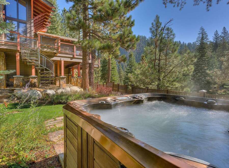 Experience ultimate relaxation in this luxurious mountain home, featuring a steaming hot tub perfect for unwinding amidst the serene forest setting.