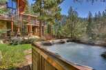 Experience ultimate relaxation in this luxurious mountain home, featuring a steaming hot tub perfect for unwinding amidst the serene forest setting.