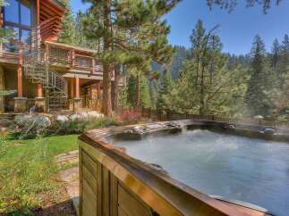 Experience ultimate relaxation in this luxurious mountain home, featuring a steaming hot tub perfect for unwinding amidst the serene forest setting.