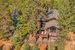 Nestled amidst towering pine trees, this charming mountain home offers a serene retreat with its expansive wooden deck, perfect for enjoying the crisp air and natural surroundings.