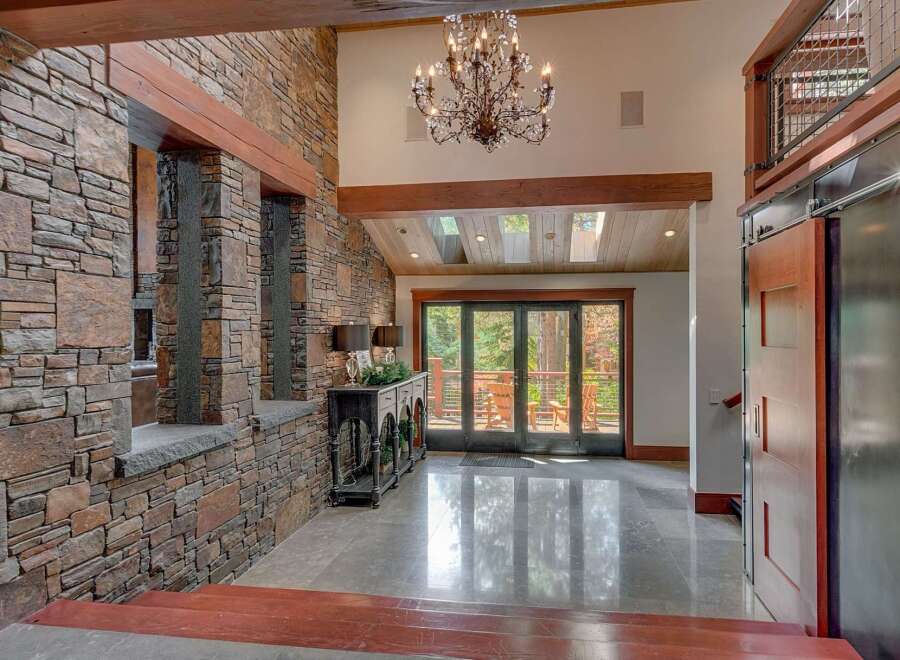 This grand entryway boasts a stunning stone accent wall and exposed wooden beams, creating a rustic yet luxurious feel.